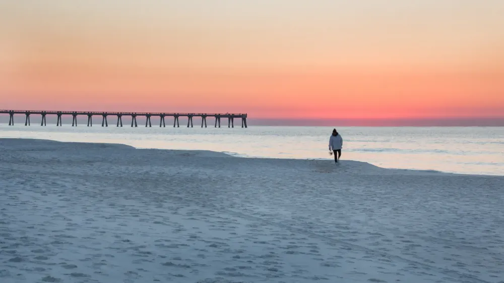 empty beach with single person walking